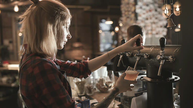 Camerie rversando una birra in un pub nella città vecchia